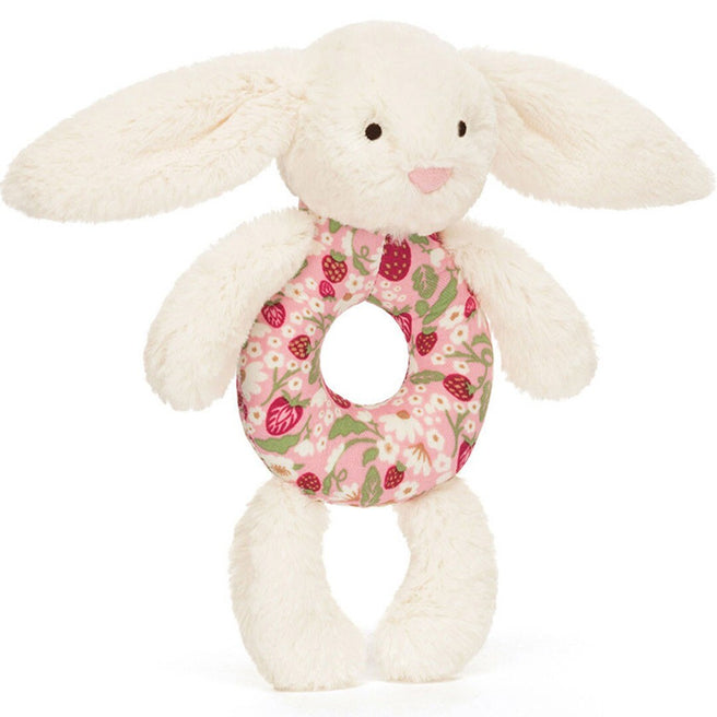 Jellycat babyspeelgoed rammelaar in de vorm van een crème konijn met een roze bloemen- en aardbeienpatroon op de buik.