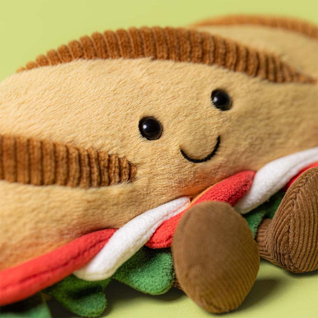 Detailopname van de Jellycat pluchen baguette caprese knuffel, met focus op het lachende gezicht en de vulling.