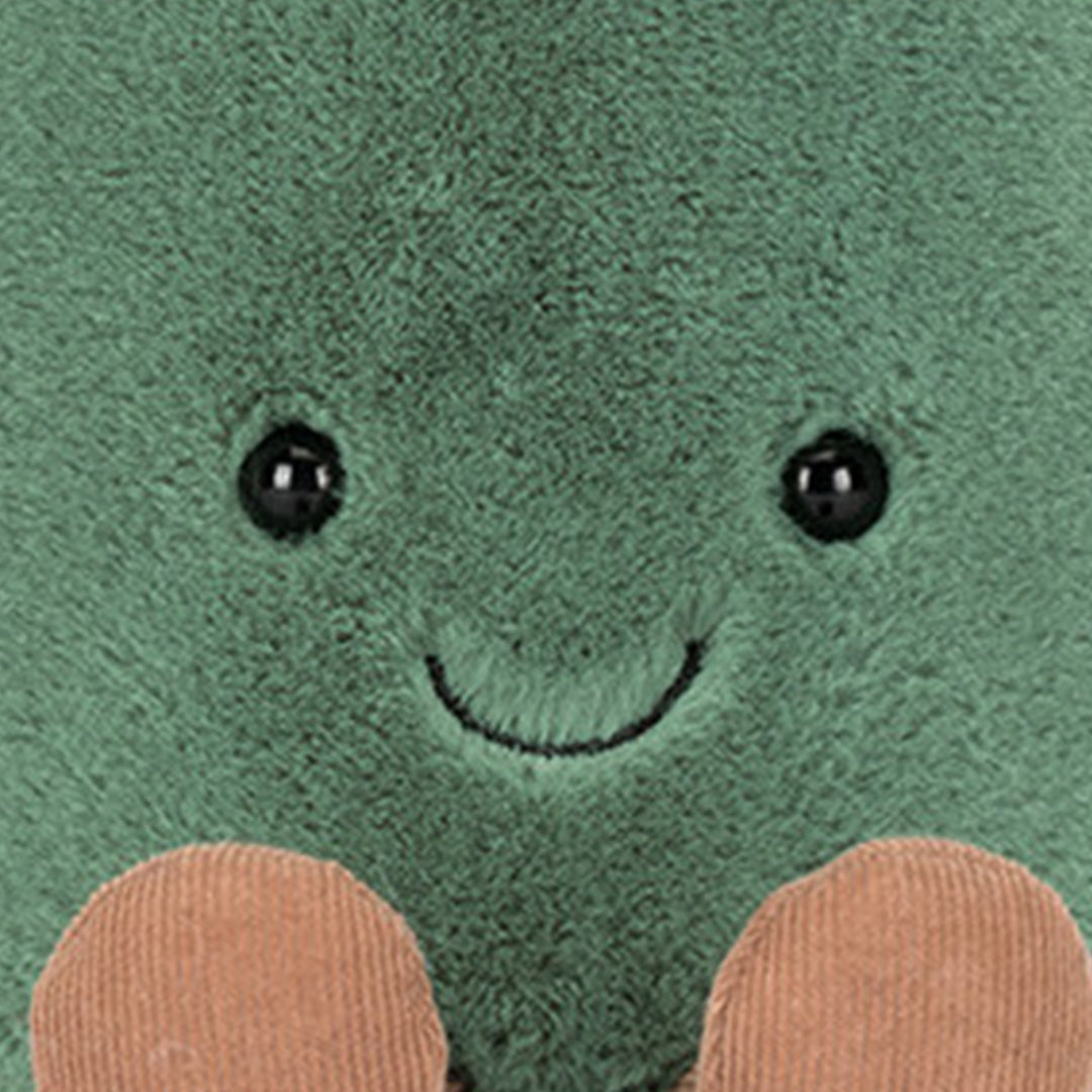 Close-up van het lachende gezicht van de groene pluche knuffelgieter met zwarte ogen.