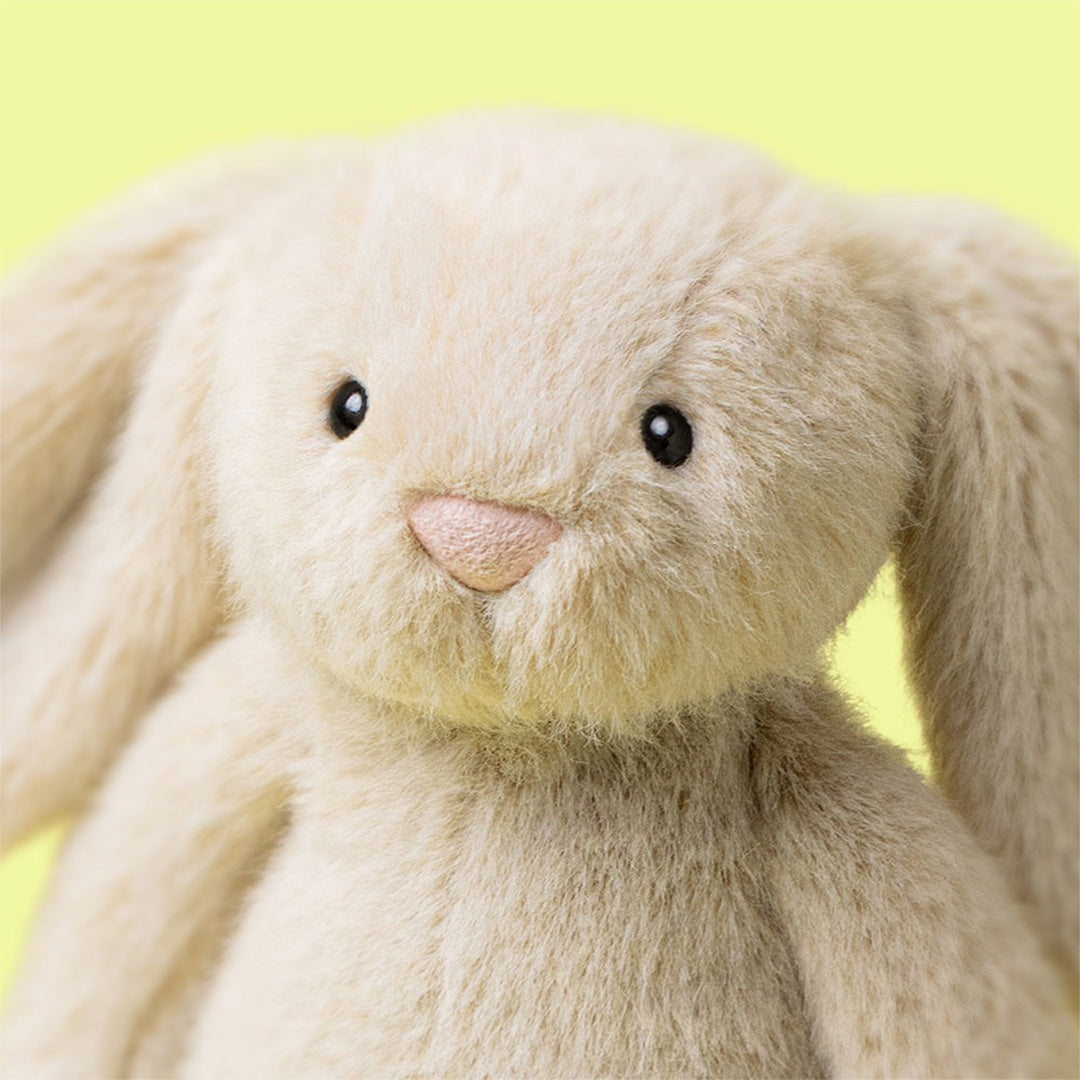 Detailopname van het gezicht van de beige Jellycat Flufflet Bunny pluchen speelgoed.