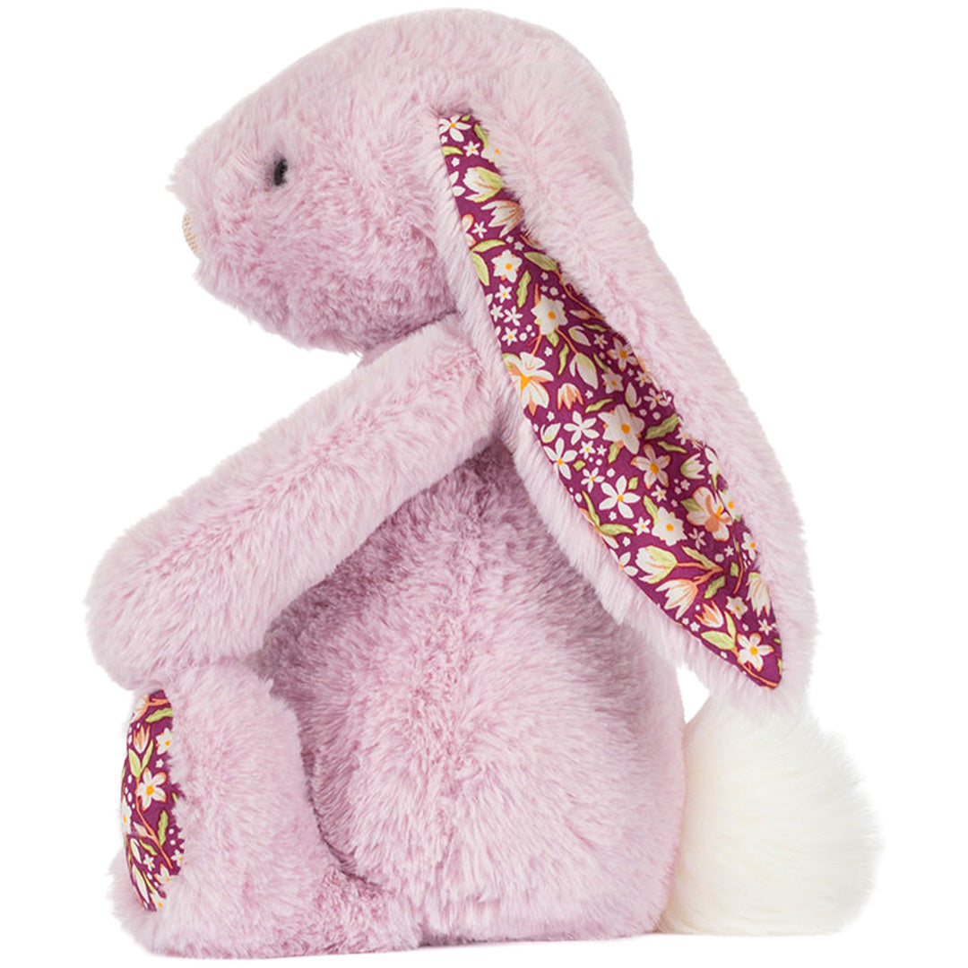 Zijaanzicht van het roze Jellycat knuffelkonijn met gebloemd oor en witte staart.