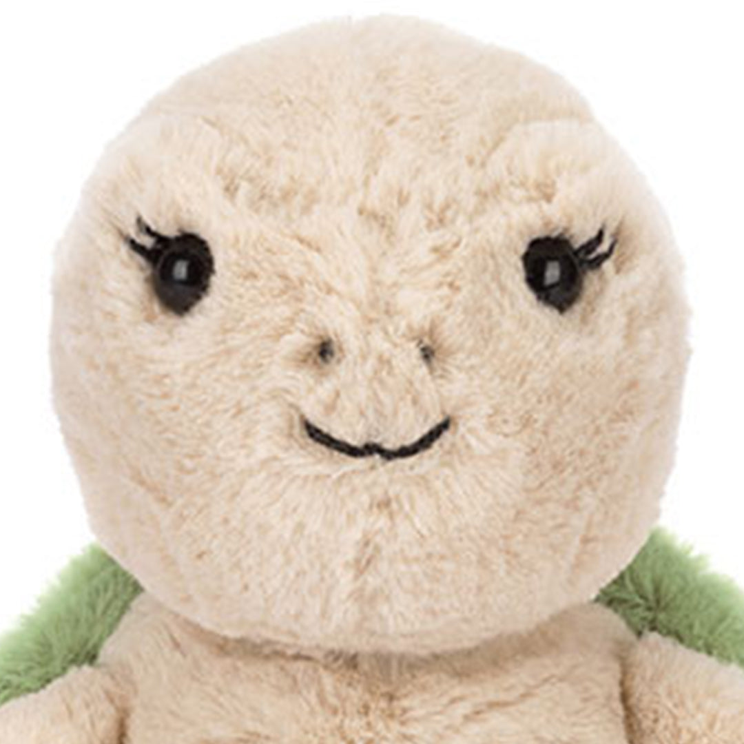 Detailopname van het gezicht van de Jellycat pluchen schildpad knuffel, met zwarte ogen en een geborduurde glimlach.