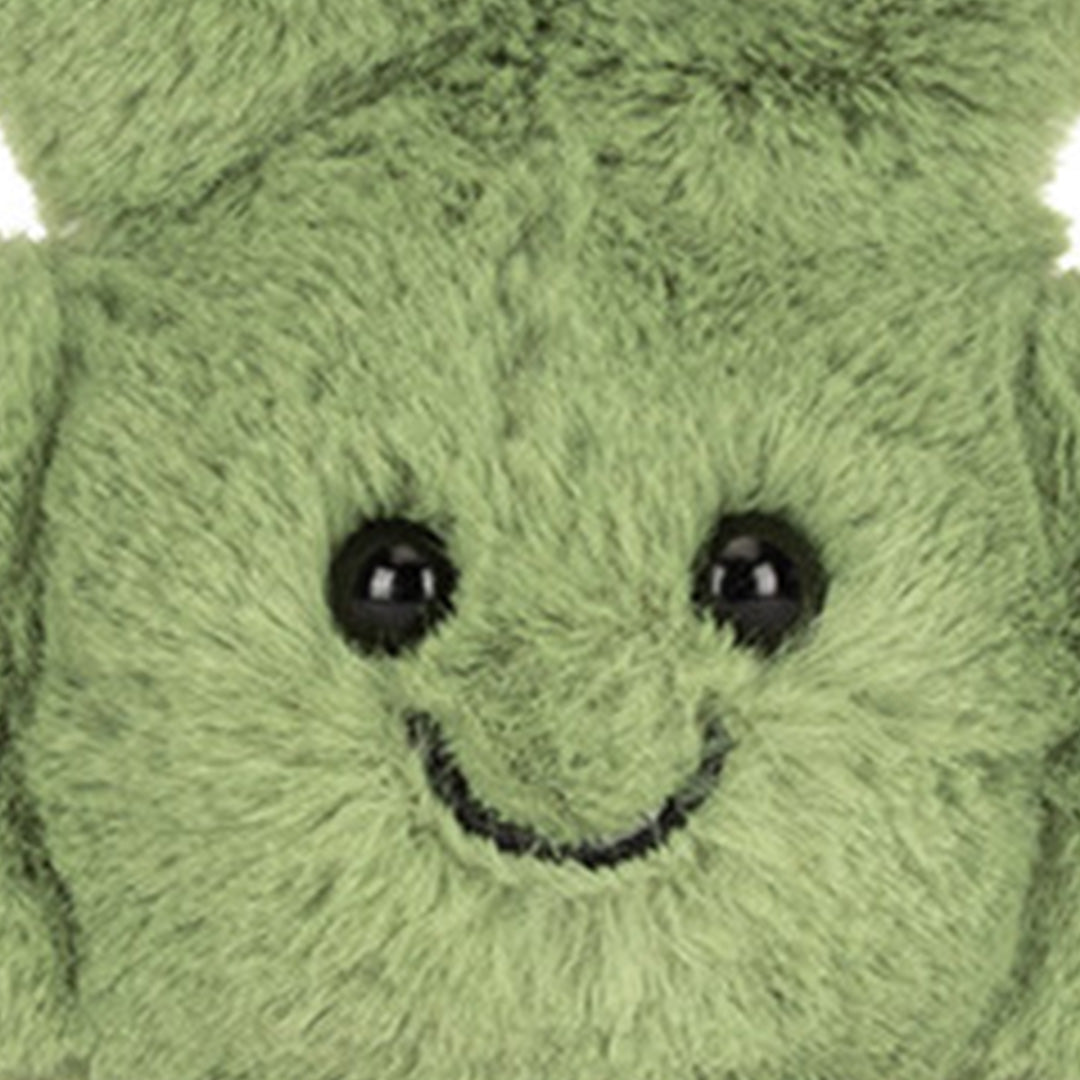 Detail van het vrolijke gezicht van de groene pluche klavertje sleutelhanger met zwarte ogen en een gestikte glimlach.