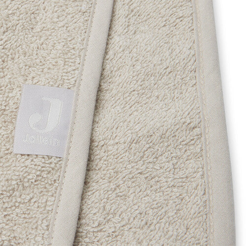 Detail van de stof en het Jollein merklabel op de nougatkleurige badponcho.