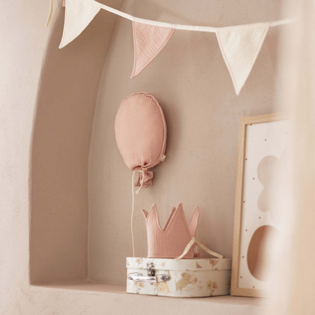 Jollein roze ballon decoratie hangend in een kinderkamer nis boven een stoffen kroon.