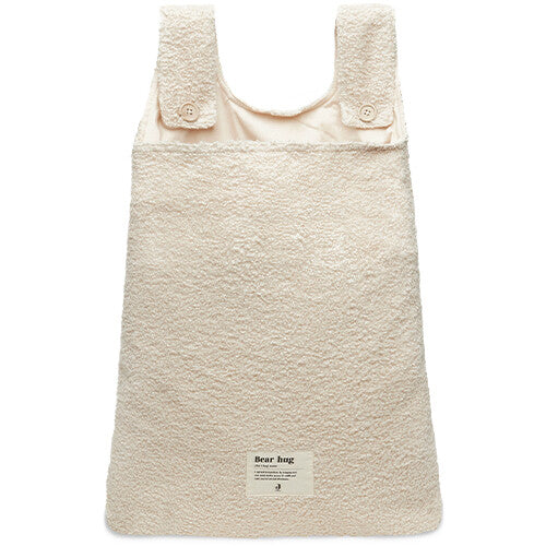 Jollein bouclé boxopbergzak in naturel kleur, plat liggend, met twee knoopbanden en een 'Bear hug' label.