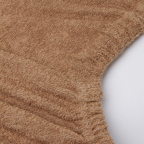 Close-up van de badstof textuur van de biscuitkleurige verschoonkussenhoes.