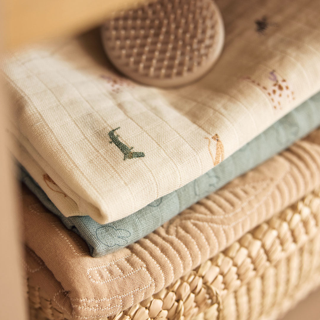 Gestapelde Jollein hydrofiele multidoeken met jungle jambo print en ander babytextiel.