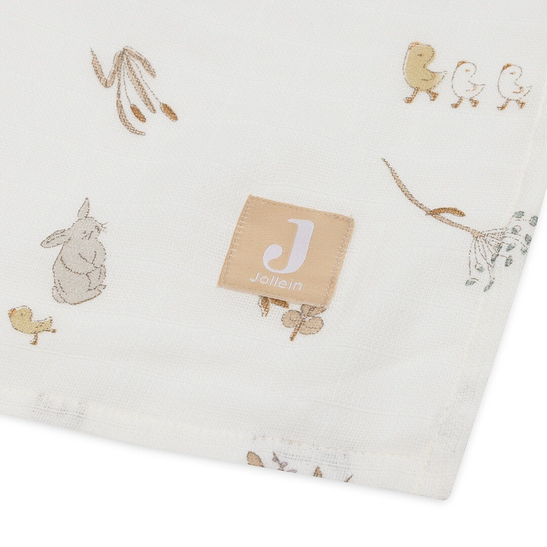 Detail van een Jollein hydrofiele multidoek met het merklabel en een patroon van een konijn, eendjes en planten.