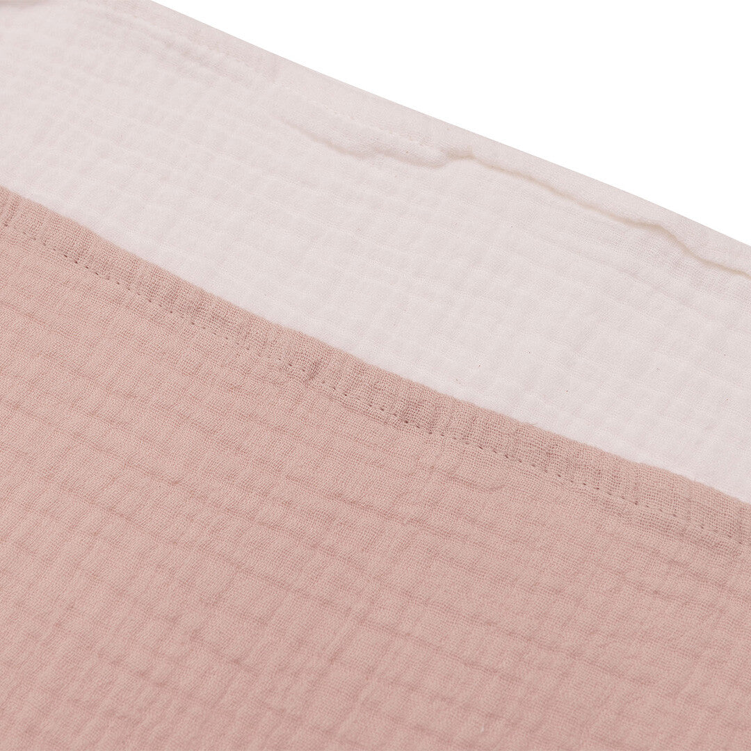Detailopname van de textuur van een Jollein hydrofiele multidoek in wild rose en een in ivory.