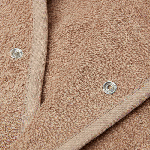 Detail van de beige badstof stof en drukknopen van de kinderbadjas.