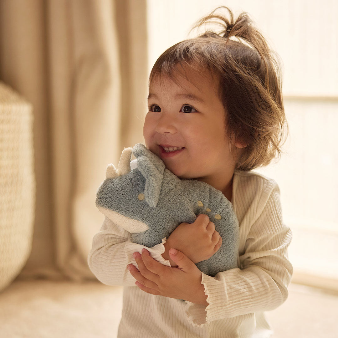 Een lachend kind knuffelt de Jollein pluchen triceratops knuffeldino.