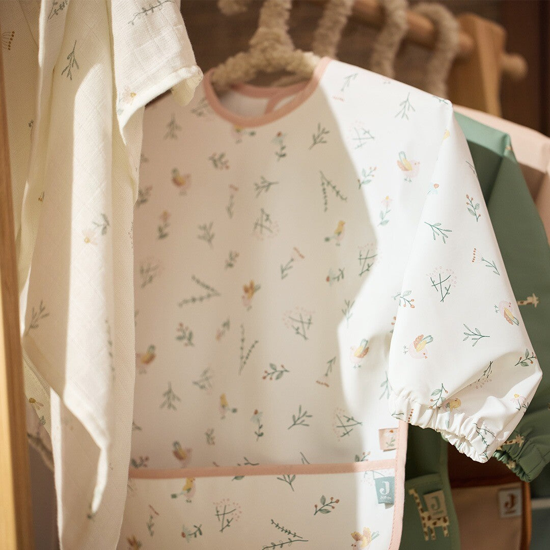 Jollein mouwslab met 'Lovely Birds' patroon hangt aan een hanger naast een witte hydrofiele doek.