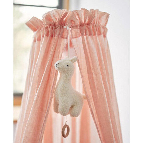 Jollein off-white pluche lama muziekspeelgoed hangend in een roze bedhemel.