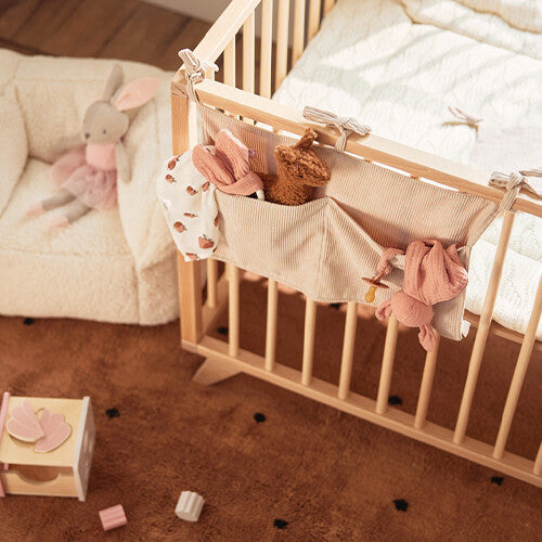 Jollein baby organizer van nougat corduroy hangend aan een houten ledikant, gevuld met babyspullen, in een kinderkamer.