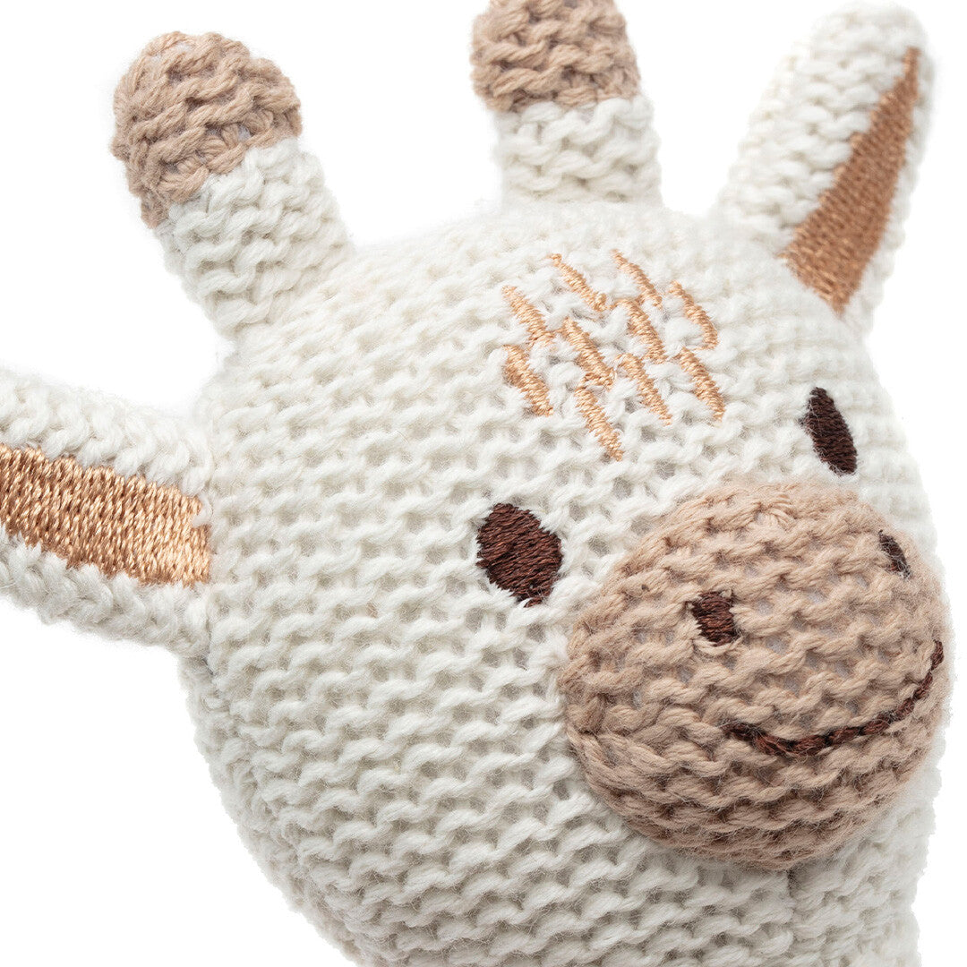 Close-up van de gebreide kop van de Jollein giraffe rammelaar met geborduurde ogen en mond.