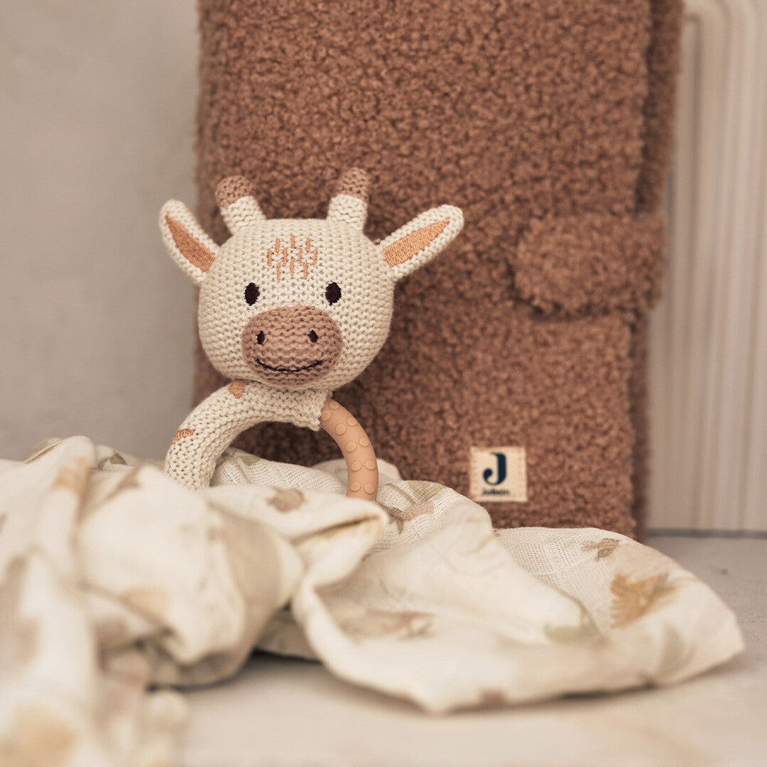 Jollein babyspeelgoed rammelaar met bijtring in de vorm van een giraffe, staand voor een bruine deken.