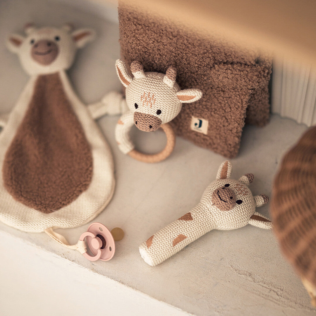 Collectie Jollein babyspeelgoed met een giraffe rammelaar, knuffeldoekje, rammelstaaf en een roze speen.