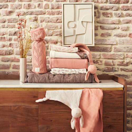 Jollein speendoek bunny ears op een stapel babytextiel op een dressoir.