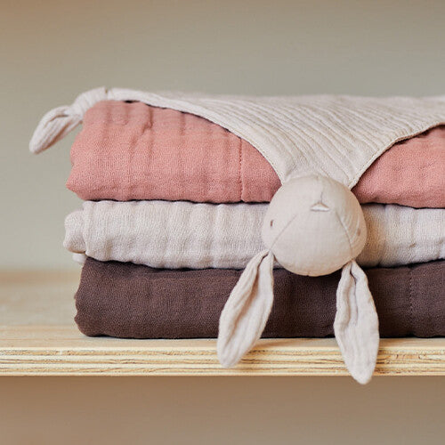 Jollein speendoek bunny ears op een stapel gevouwen babydekens.