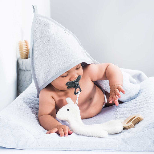 Een baby speelt met de Jollein off-white pluchen lama speendoek op een aankleedkussen.