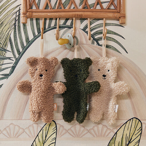 Drie Jollein teddy bear speendoekjes in beige, groen en crème hangen aan een kapstokje.