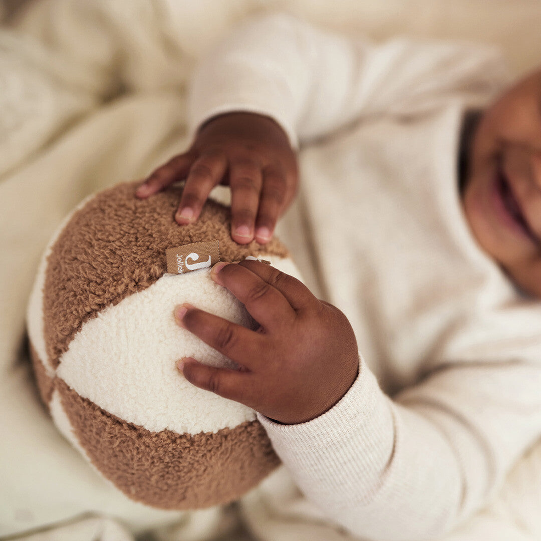 Babyhandjes houden de Jollein stoffen speelbal vast.