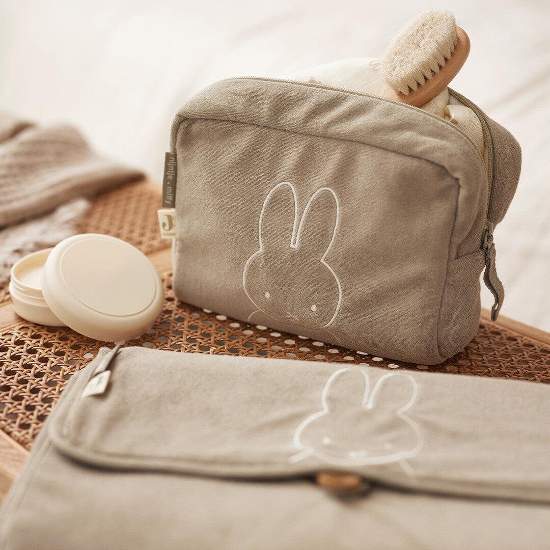 Open Jollein badstof toilettas met Miffy-opdruk, een borstel erin en een crème potje ernaast.