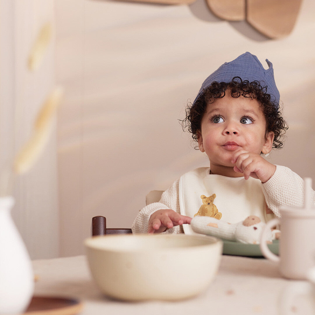 Een kind draagt de Jollein blauwe stoffen verjaardagskroon tijdens het eten.