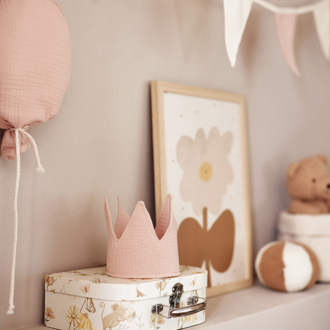 Jollein roze stoffen verjaardagskroon op een decoratieve koffer in een kinderkamer.