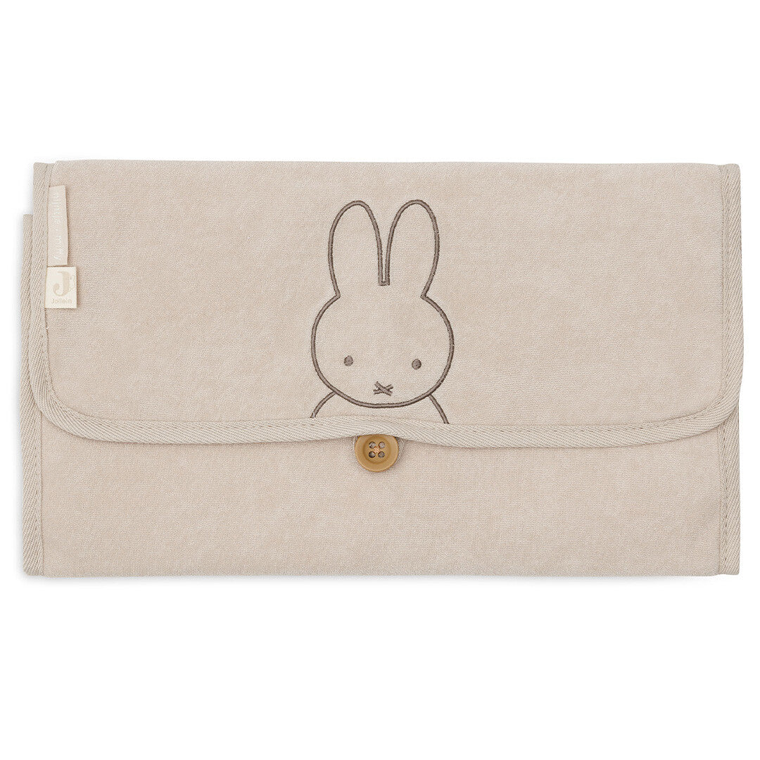 Jollein baby verschoonmat van badstof in nougatkleur, opgevouwen met geborduurde Miffy en houten knoopsluiting.