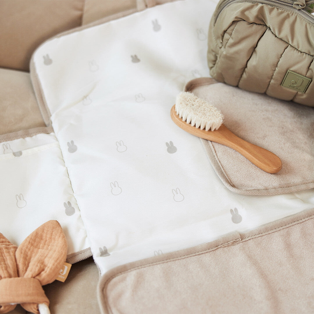 Jollein baby verschoonmat van badstof met Miffy patroon, opengevouwen met een babyborstel en tasje ernaast.