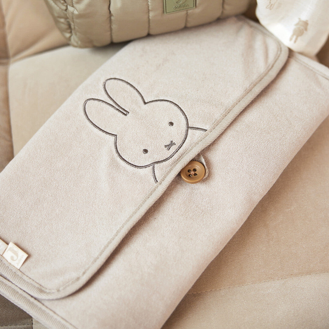 Jollein baby verschoonmat van badstof in nougatkleur, schuin van bovenaf gefotografeerd met geborduurde Miffy.