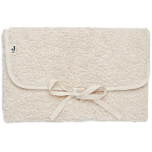 Jollein bouclé verschoonmat in naturel kleur, opgevouwen en dichtgebonden met een strik.