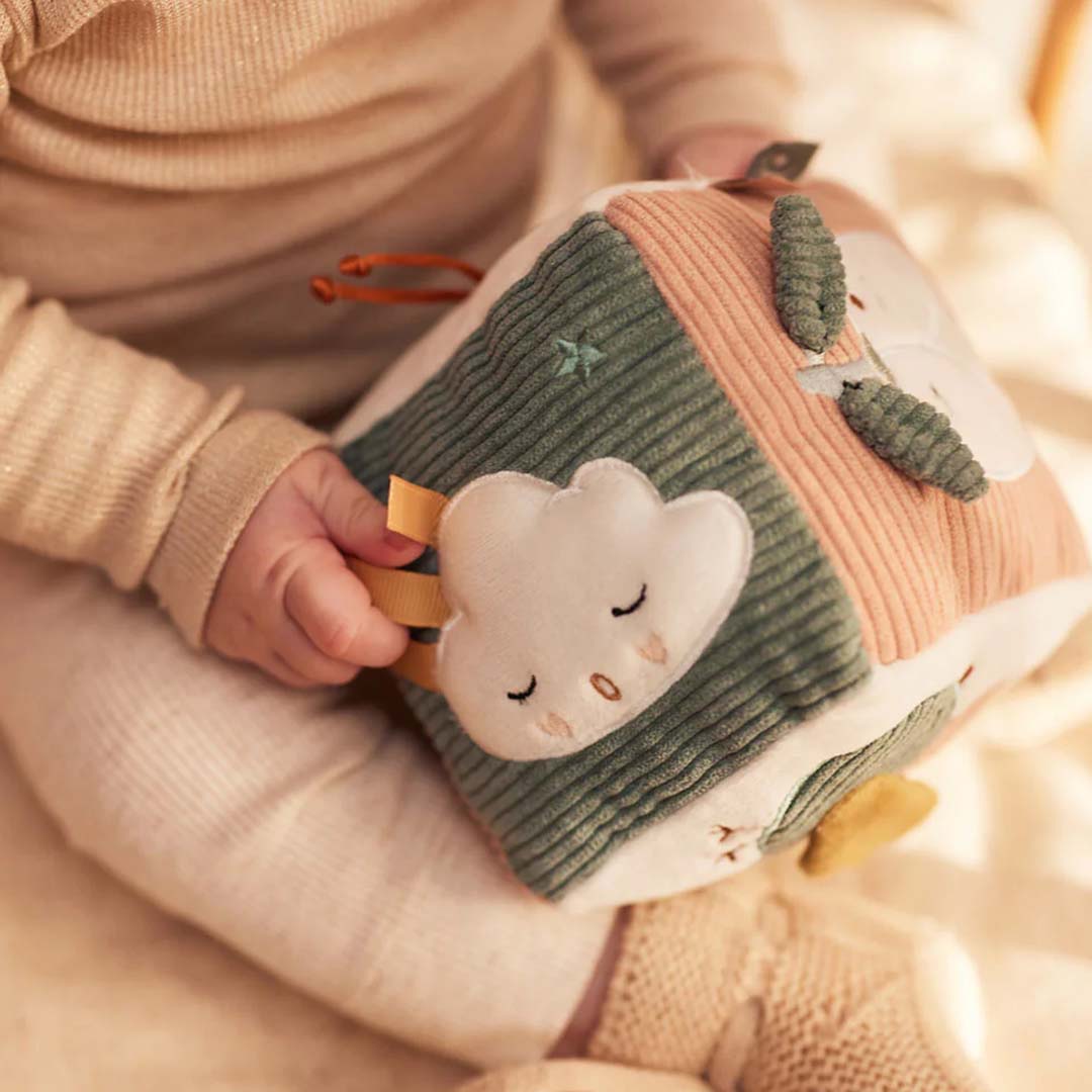 Babyhandjes houden de Jollein activiteitenkubus vast, met een wolkje erop.