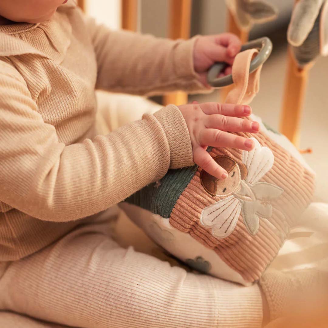 Babyhandjes houden de Jollein activiteitenkubus vast, met een fee erop.