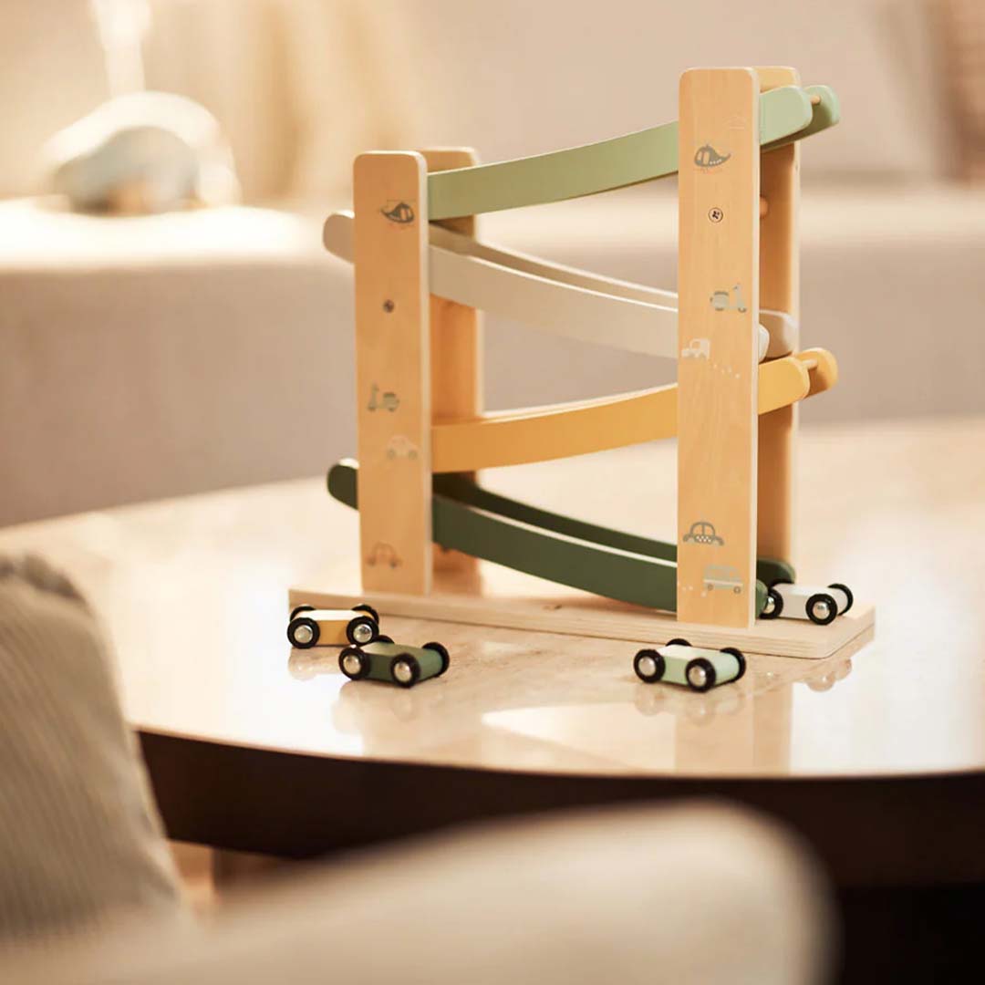 De Jollein houten autobaan staat op een houten tafel met drie autootjes ernaast.