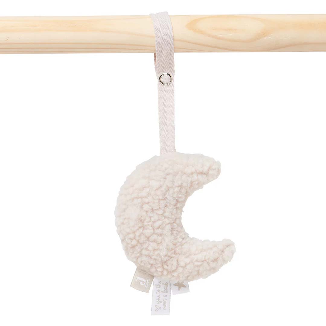 Close-up van een beige polyester maan-vormig speeltje hangend aan een houten staaf.
