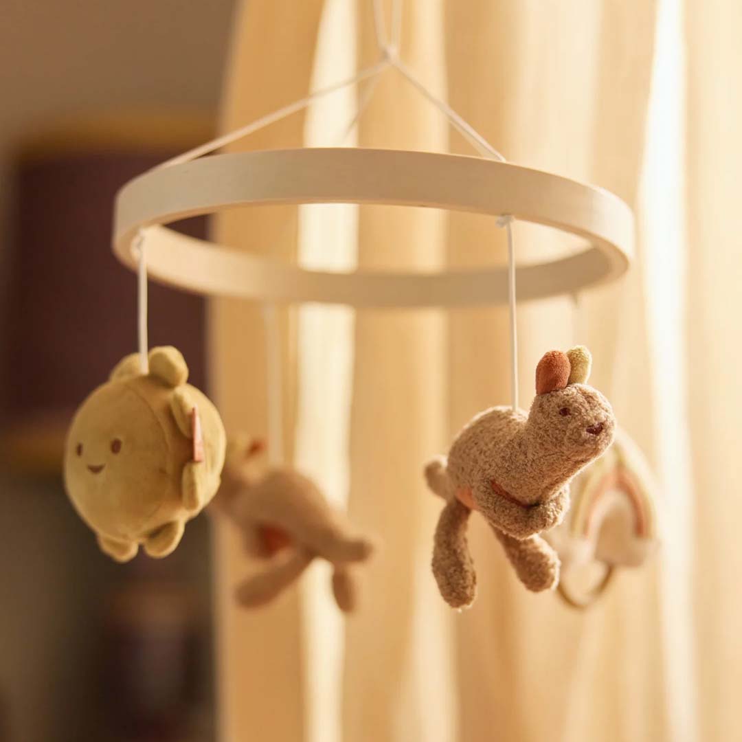 Jollein babymobiel met pluchen kangoeroes, zon en regenboog hangend voor een raam met gordijnen.