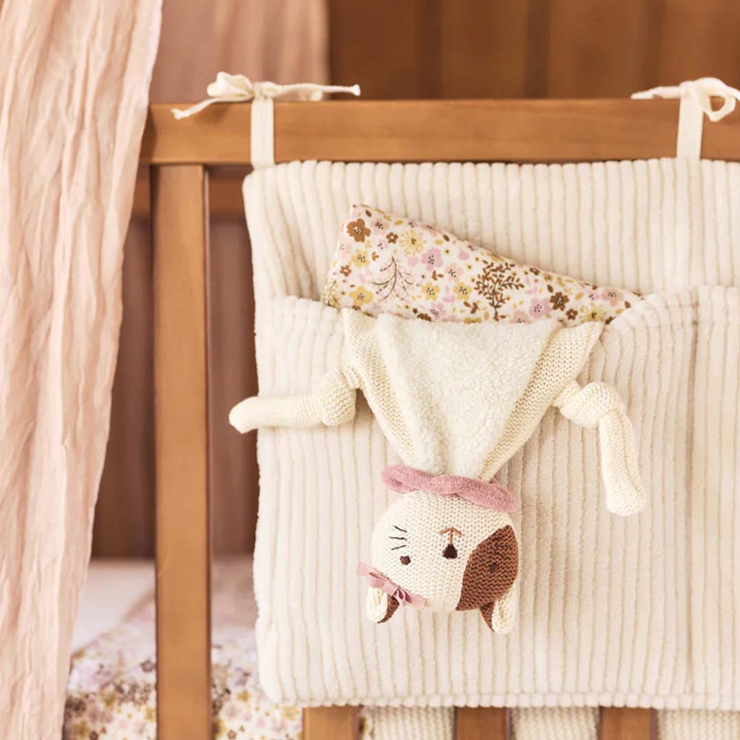 Jollein speendoek kat Jill hangt ondersteboven in een crèmekleurige bedorganizer in een babybedje.