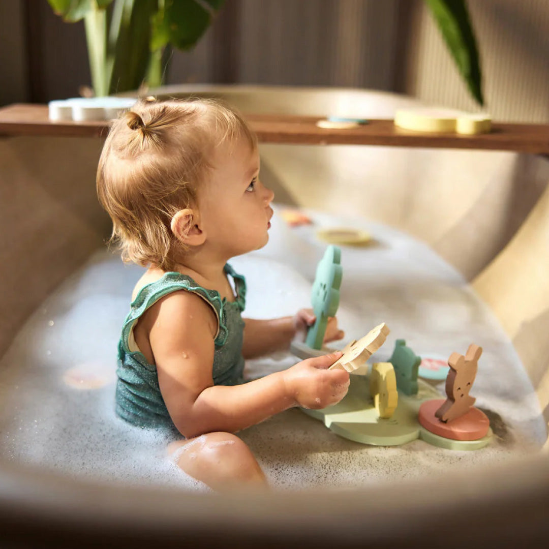 Een baby speelt in bad met de Jollein badspeelset, bestaande uit drijvende schuimfiguren.