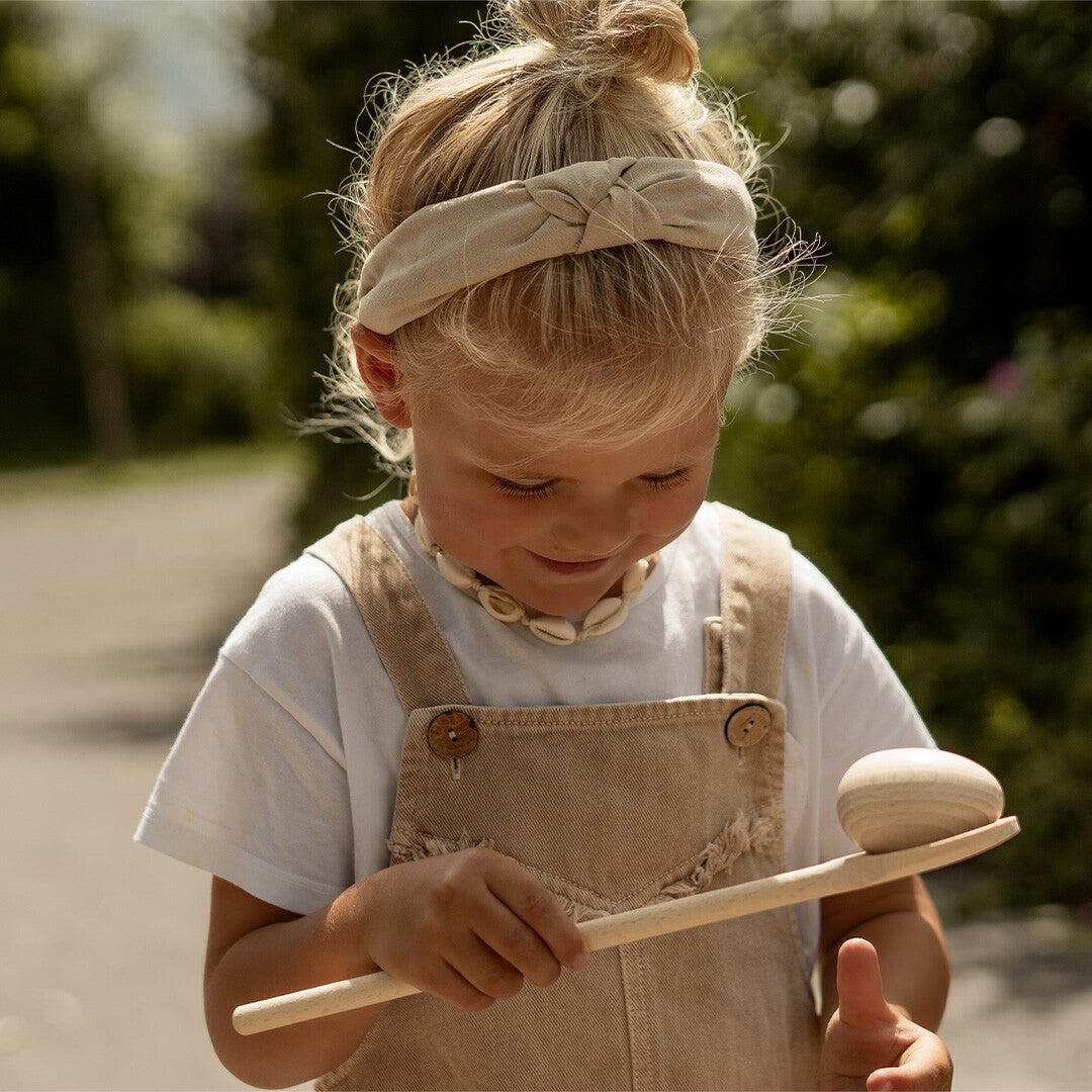 Een kind speelt met het kids at work houten eierloop spel, balancerend met een ei op een lepel.