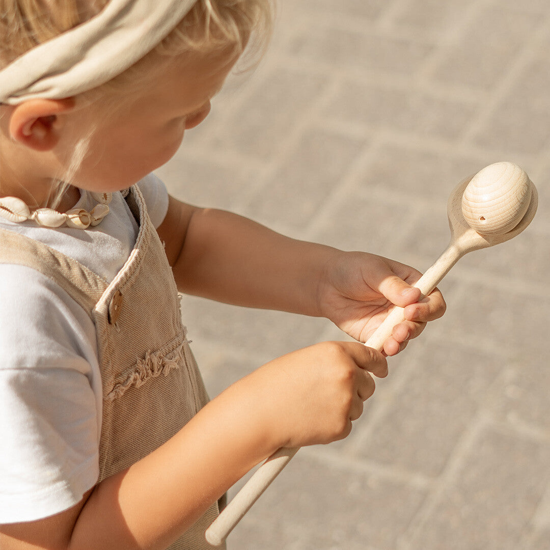 Detail van een kind dat het kids at work houten eierloop spel vasthoudt, met een ei op de lepel.
