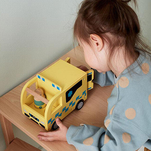 Een kind speelt met de Kids Concept houten speelgoed ambulance op een houten tafel.