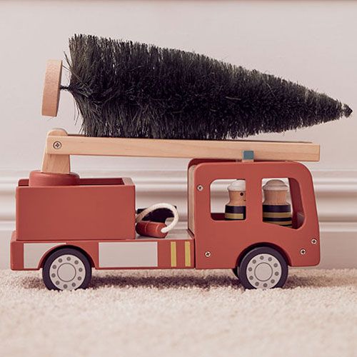 Kids Concept houten brandweerauto met een kerstboom op de ladder, staand op een vloerkleed.