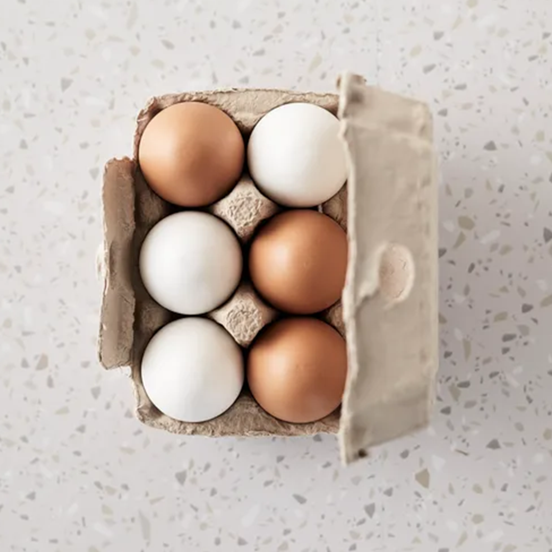 Kids Concept houten speelgoedeieren in een open kartonnen doos, van bovenaf gezien, met afwisselend witte en bruine eieren.