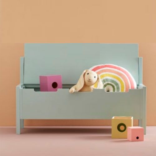 Kids Concept mintgroene kinderbank met opbergruimte gevuld met speelgoed zoals een knuffelkonijn en een regenboogkussen.