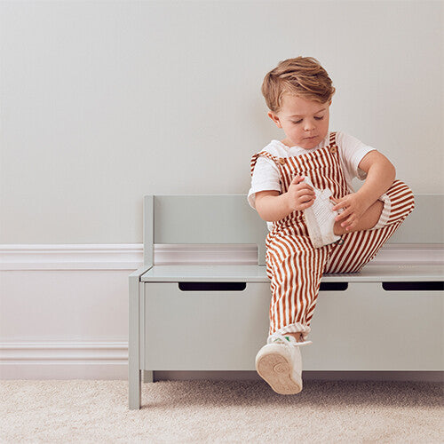 Een kind zit op de Kids Concept mintgroene kinderbank met opbergruimte.