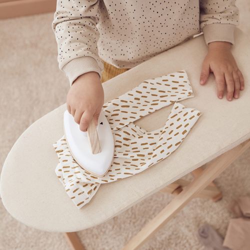 Een kind strijkt een kledingstuk op de kids concept speelgoed strijkplank.