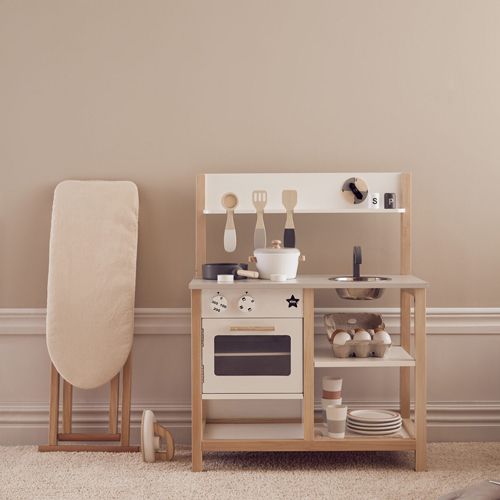 Kids concept speelgoed strijkplank gevouwen naast een houten speelgoedkeuken.